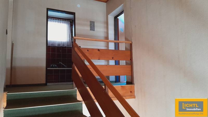 The interior of a hallway with stairs and doors leading to various rooms.