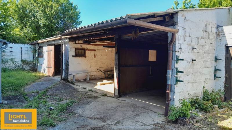 A tin garage with open doors, surrounded by greenery in Joise, Apartment construction.