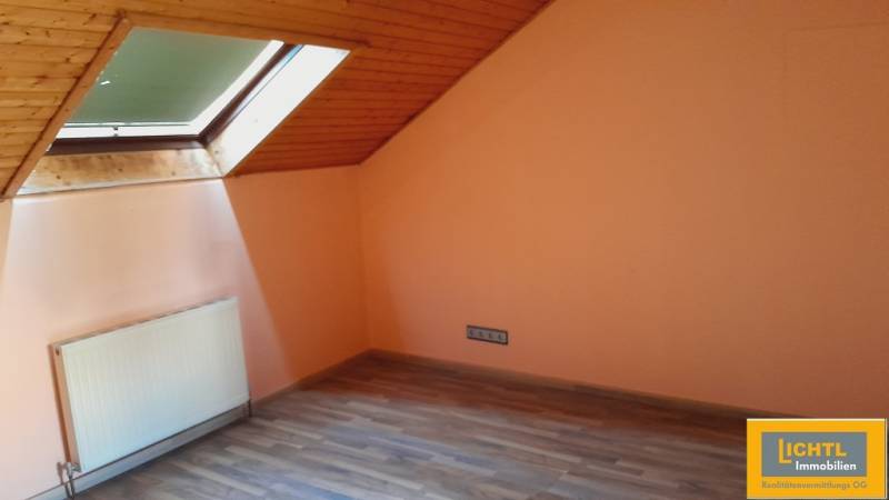 Attic room with a window and radiator, suitable for apartment construction.