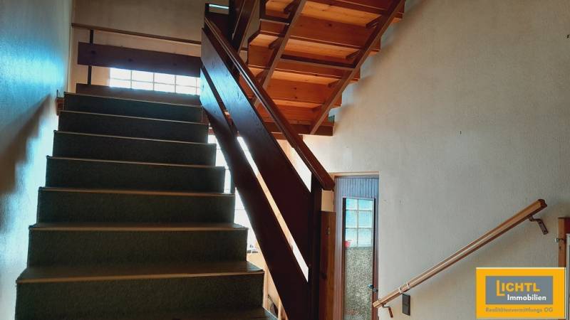 A staircase with wooden railing and carpeted steps within the construction of apartments.