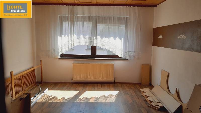 Interior of a room with parquet flooring, a window with a curtain, and a radiator – Apartment construction.