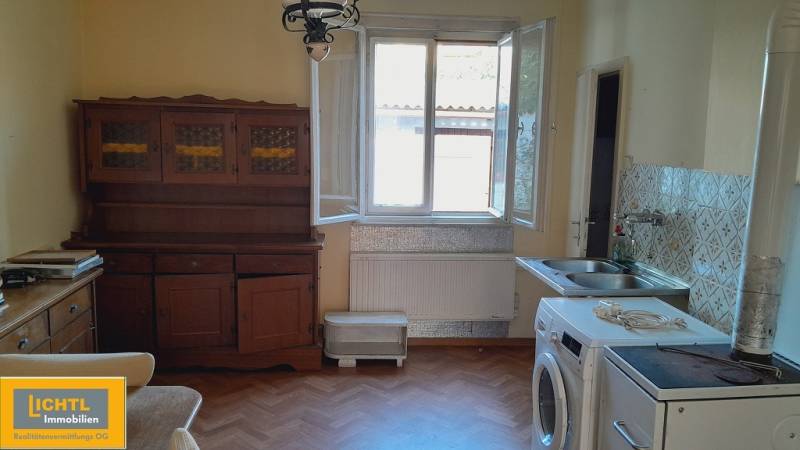A kitchen with a sink, furniture, a washing machine, and tiles. Apartment construction.