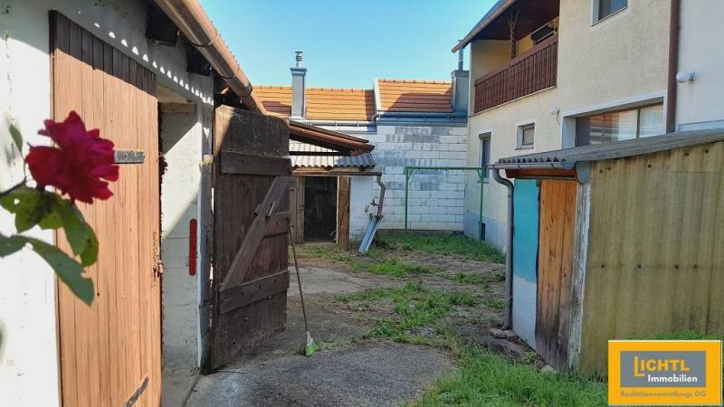 A courtyard in Jois with houses and old wooden shelters for apartment construction.