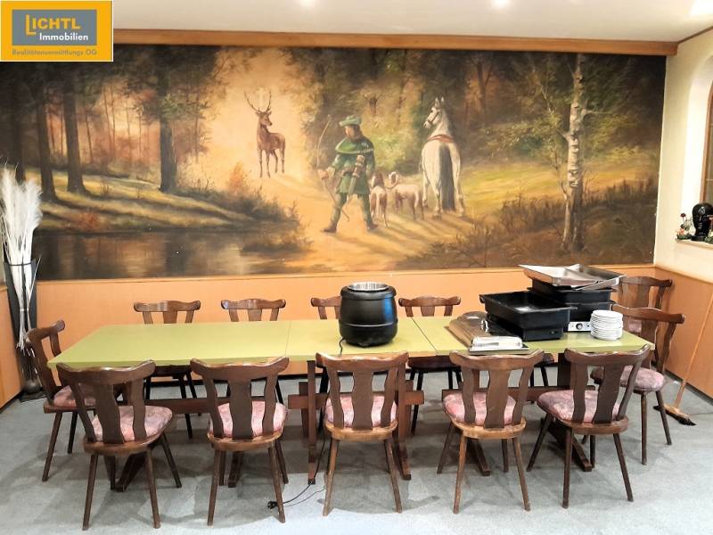 Eleven chairs and a table in a dining area with a forest mural on the wall.