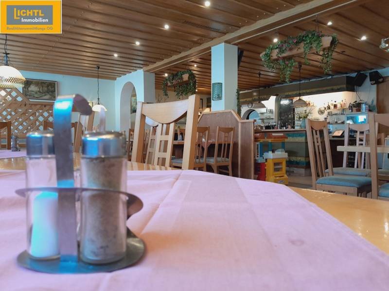 Interior of a dining area with a wooden ceiling, plants, and tables with spice containers.