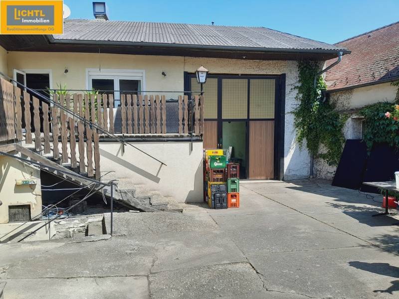 A courtyard with a staircase in the Gastro area in Grossinzersdorf, surrounded by greenery and beer crates.