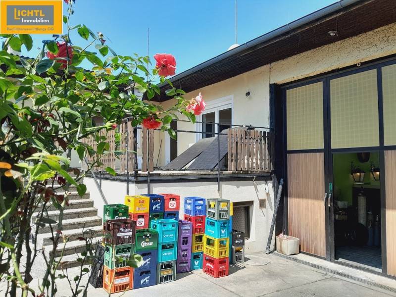 Flower-filled gastro spaces in Grossinzersdorf, with colorful crates in the yard next to the building.
