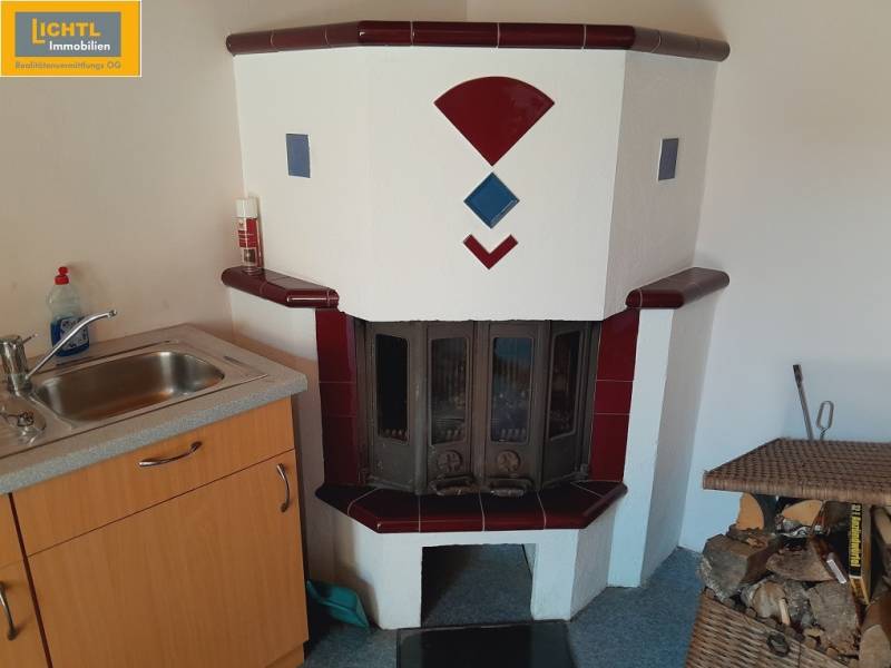 A fireplace next to the kitchen sink in a gastro area with wood for heating.