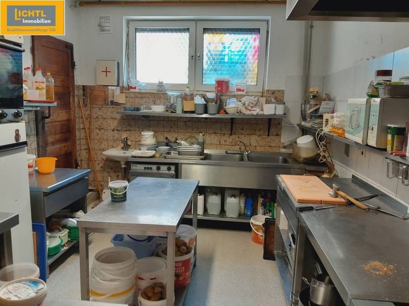 Kitchen in a gastro space with tables, containers, and cooking equipment.