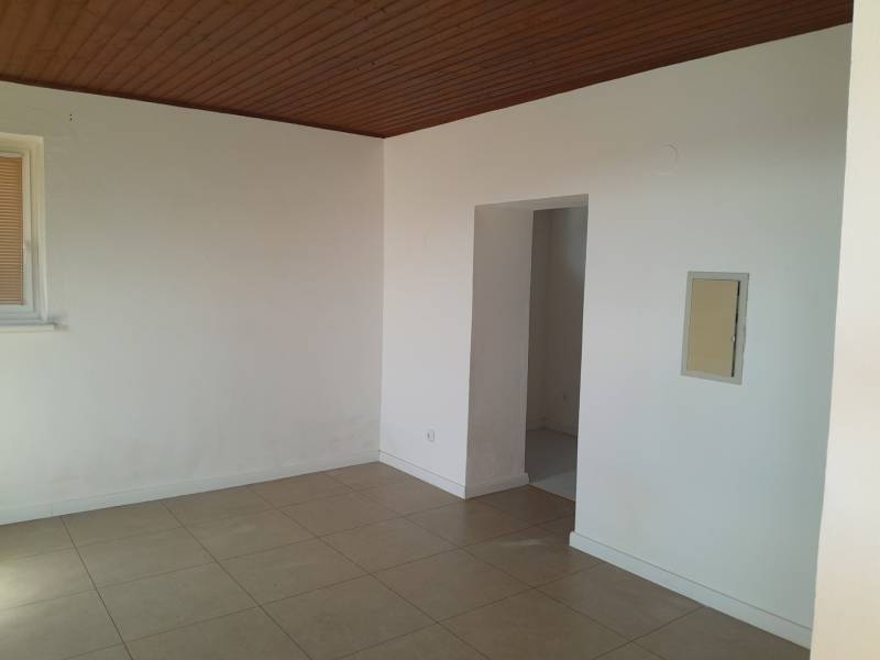 The interior of a commercial space with white walls, a brown ceiling, and tiles.