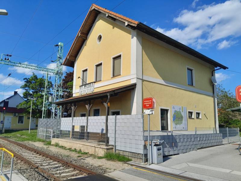 The yellow railway station building in St. Andrä am Zicksee with a train warning.