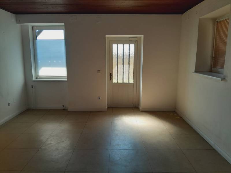 An empty interior with white walls, tiles, and a closed window in commercial premises.