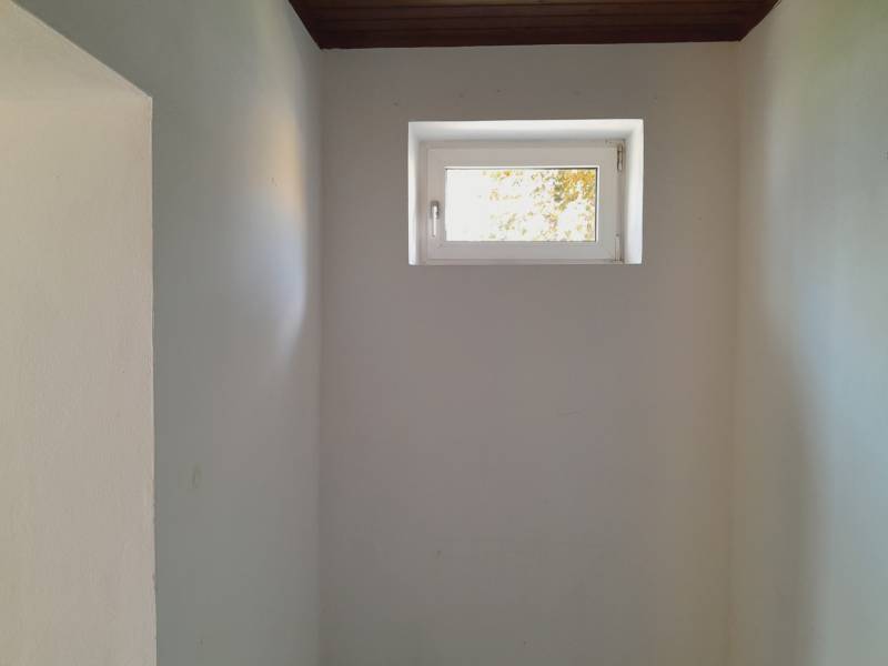 A small window in narrow commercial premises, white walls, dark ceiling.