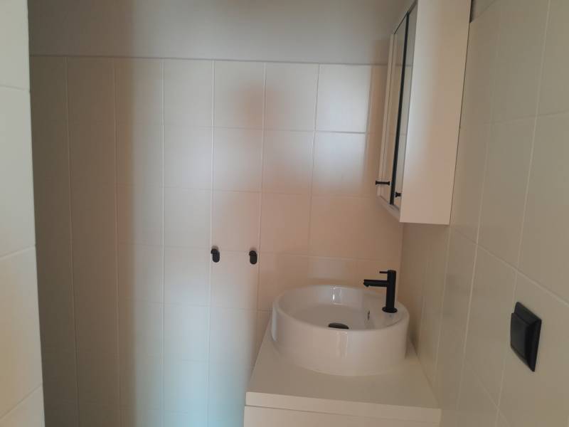 Bathroom commercial spaces with a sink and cabinet in neutral tones.