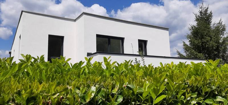 A villa in Hainburg an der Donau with a white facade, surrounded by greenery under a blue sky.