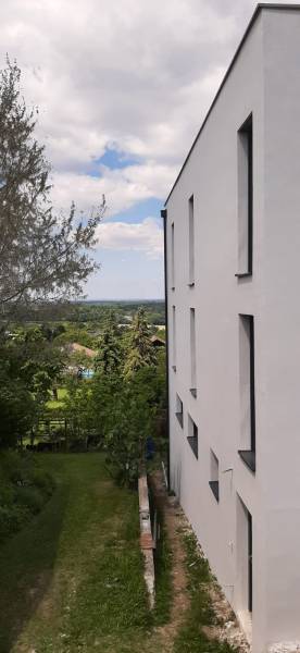 The white facade of the villa in Hainburg an der Donau overlooking the garden and trees.