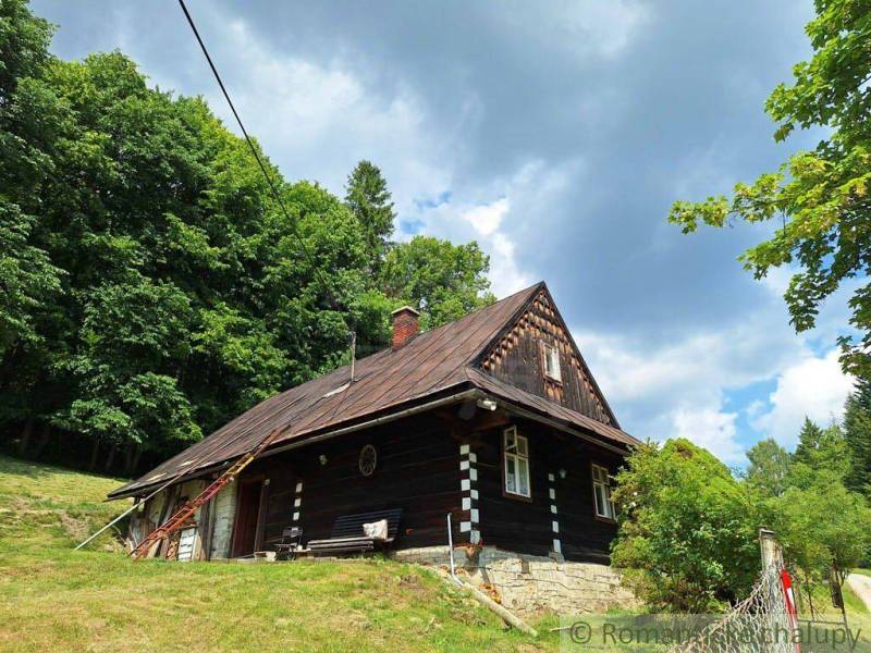 A cottage in Zákopčie surrounded by forests and beautiful nature under a cloudy sky.