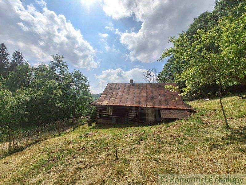 A cottage in Zákopčie surrounded by nature and forests under a blue sky.