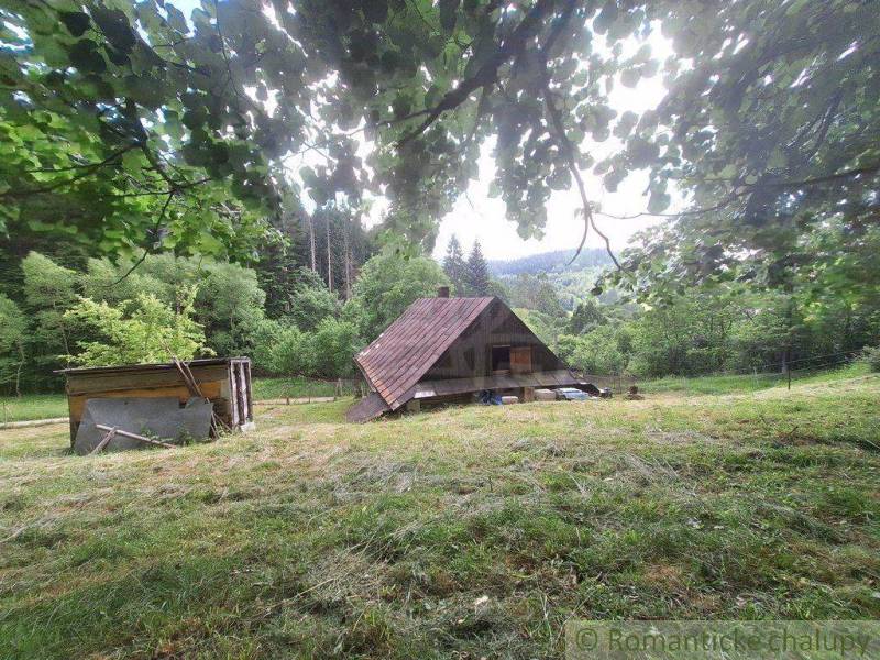 A cottage in Zákopčie surrounded by green nature and hills in the background.