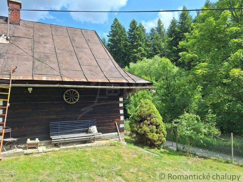 A cottage in Zákopčie surrounded by forests, with a bench and wooden details.