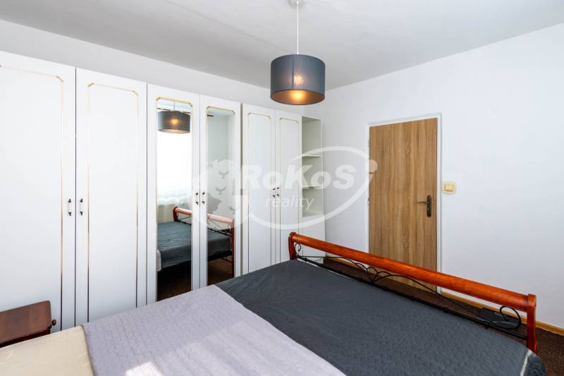 Bedroom in a 2-room apartment with a bed, wardrobes, and a mirror.