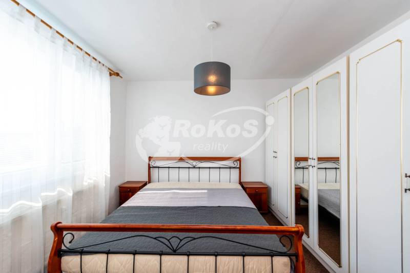 A simply furnished bedroom with a wardrobe and a large window in a 2-room apartment.
