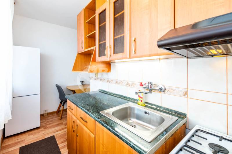 A kitchen in a 2-room apartment with light wooden furniture and appliances.