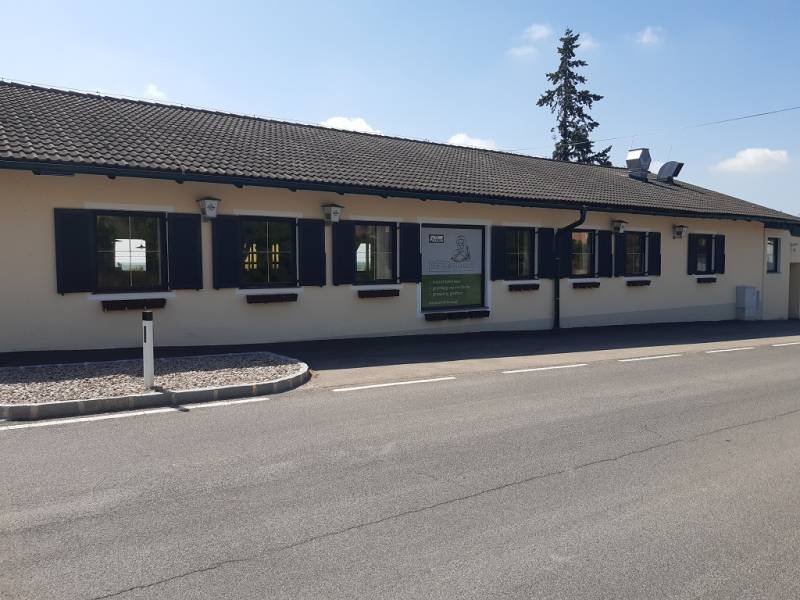 The exterior of the building on Hornerstraße with dining spaces and parking in front of the entrance.