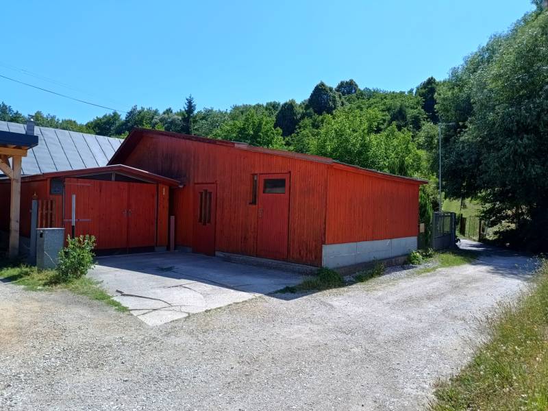 A cottage in Tužina with a gable roof surrounded by greenery.