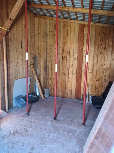 The interior of a cabin with wooden walls and support columns.