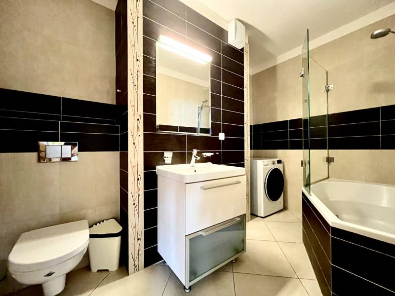 Bathroom in a 2-room apartment with a bathtub, toilet, and washing machine.