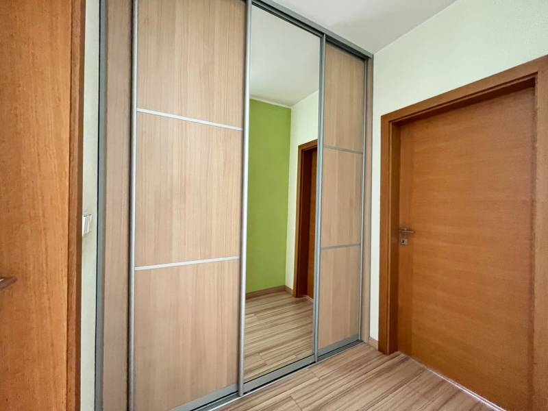 A hallway in a 2-room apartment with a mirrored wardrobe and wooden doors.