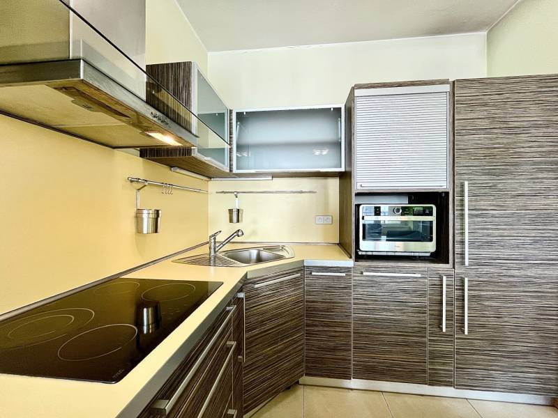A kitchen in a 2-room apartment with a corner unit, a hob, and built-in appliances.