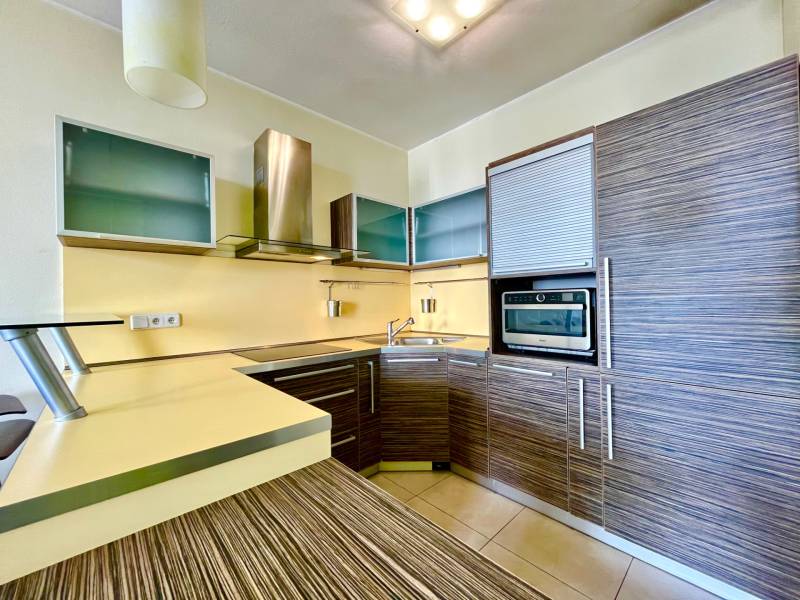 A kitchen in a 2-room apartment with wooden cabinets and built-in appliances.