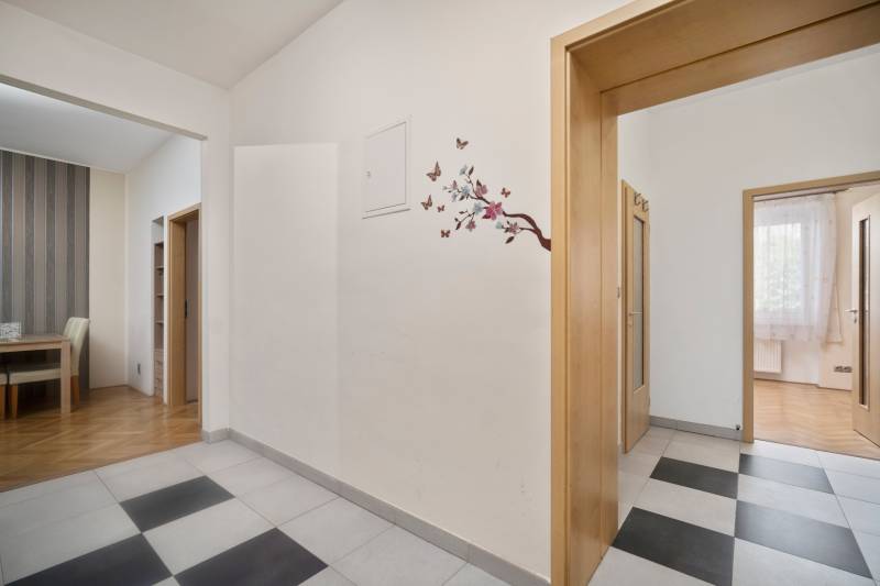 Entrance hall in a 3-room apartment with floral decoration on the wall and wooden doors.