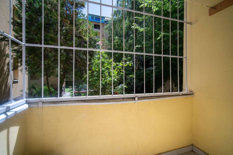 A small balcony with a view of greenery and wooden elements in a 3-room apartment.