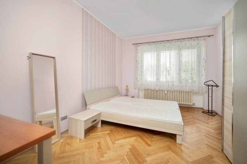 Bedroom in a 3-room apartment with a bed, mirror, and wooden floor.