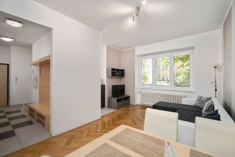 Living room with a sofa, dining table, and hallway in a 3-bedroom apartment.