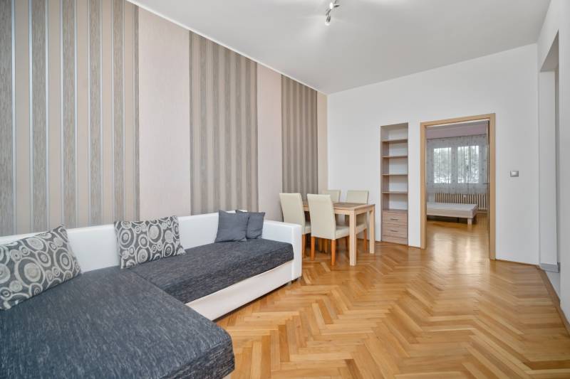 Living room with orange wooden furniture, a sofa, and a dining table in a three-room apartment.