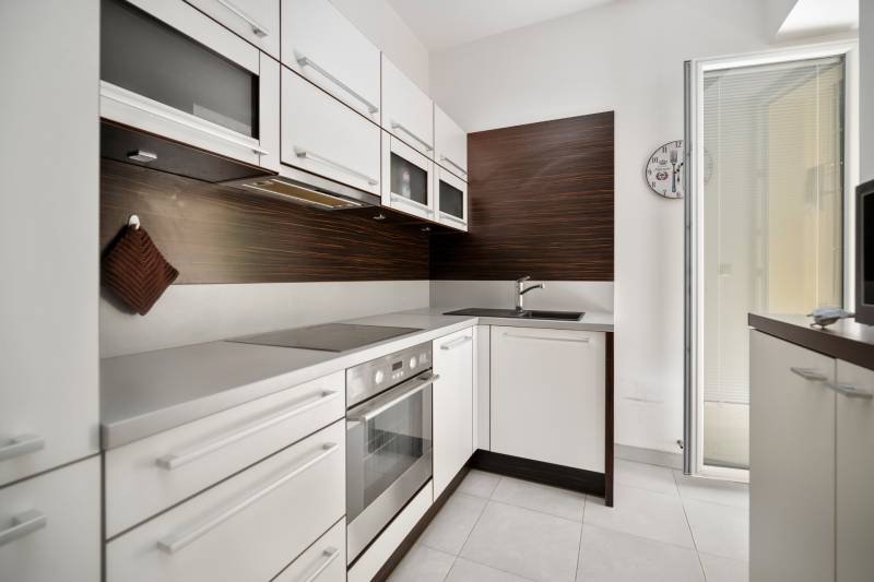 A kitchen in a 3-room apartment with white cabinets and built-in appliances.