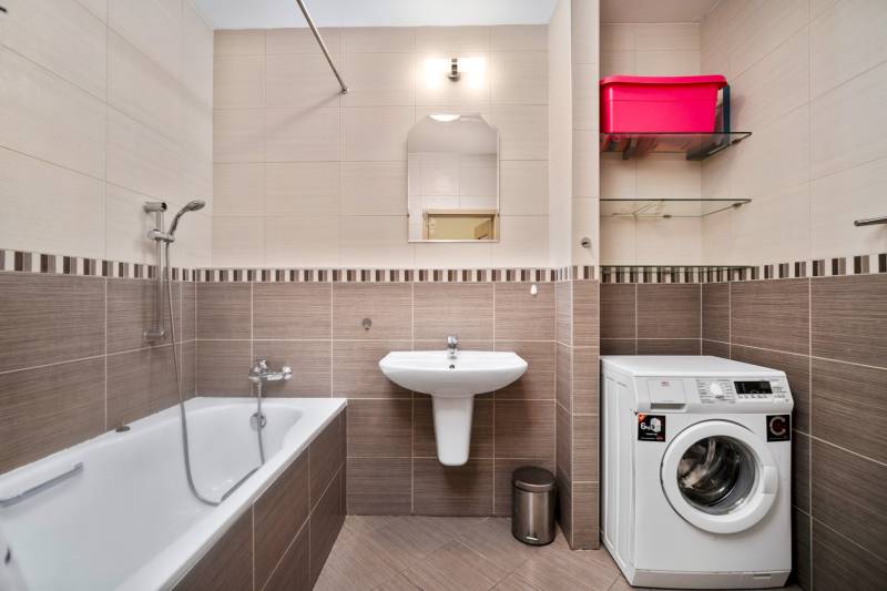 Bathroom in a 3-room apartment with a bathtub, washing machine, and sink.