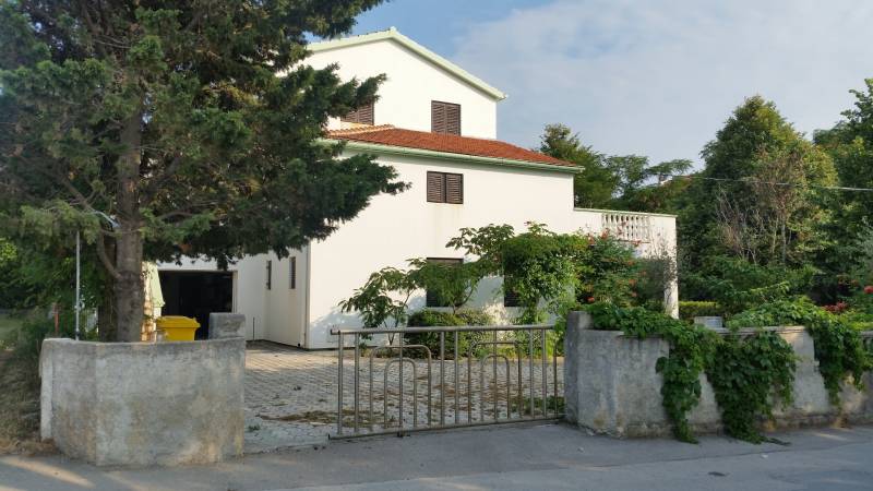 A family house in Vrsi with a white facade, red roof, and surrounding greenery.