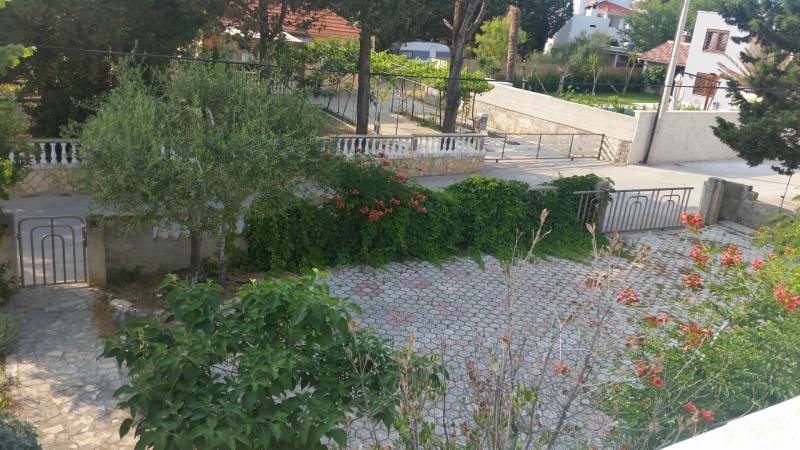The garden of a family house in Vrsi with paving, greenery, and flowers.