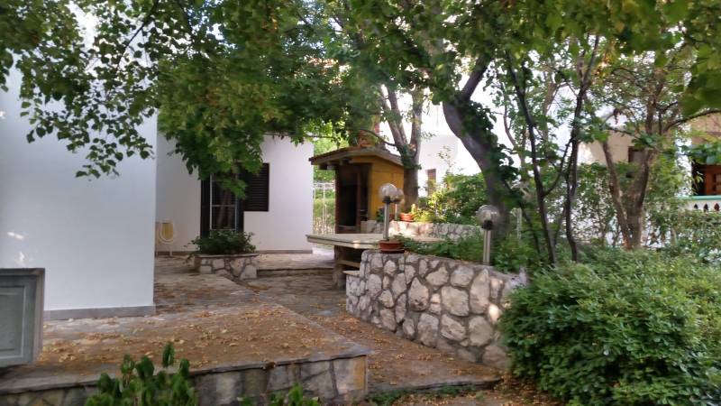 A family house in Vrsi surrounded by trees and stone elements.