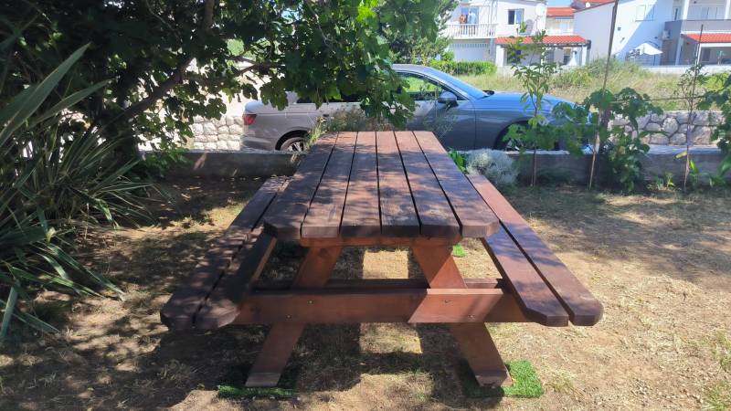 A wooden picnic table in the shade in the garden of a family house in the town of Vrsi.