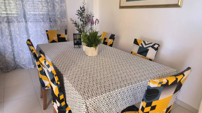 A dining table with a flower and six colorful chairs in a family house.