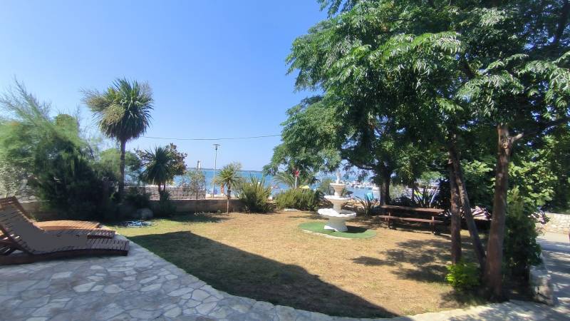 A garden at a family house in Vrsi with palm trees, a fountain, and a view of the sea.