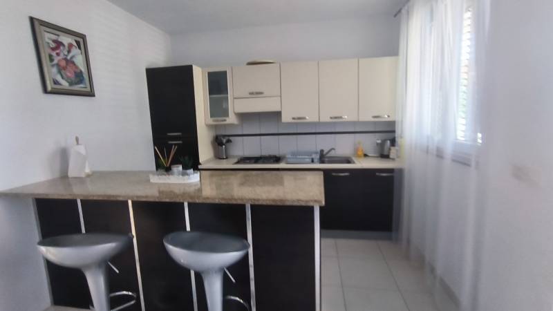 A kitchen in a family house with a bar counter, stools, and light cabinets.