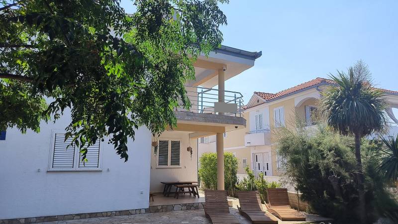 A family house in Vrsi with a terrace, benches, and greenery in the surroundings.