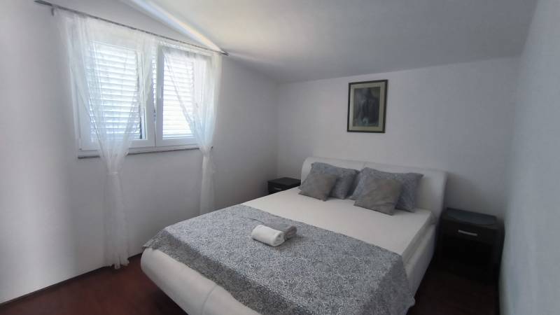 Bright bedroom with a large bed, pillows, painting, and curtain in a family house.